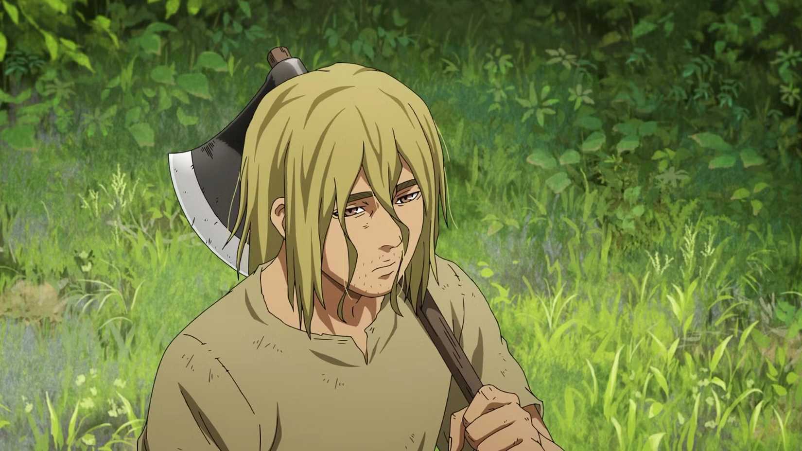 A sad looking Thorfinn holds an axe in the woods in Vinland Saga Season 2