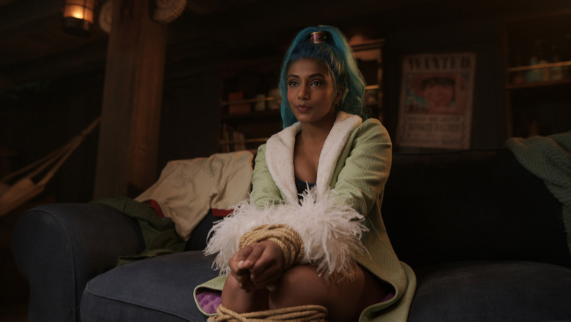 Charithra Chandran dans le rôle de Miss Wednesday est assise, les jambes croisées dans la saison 2 de Netflix One Piece 