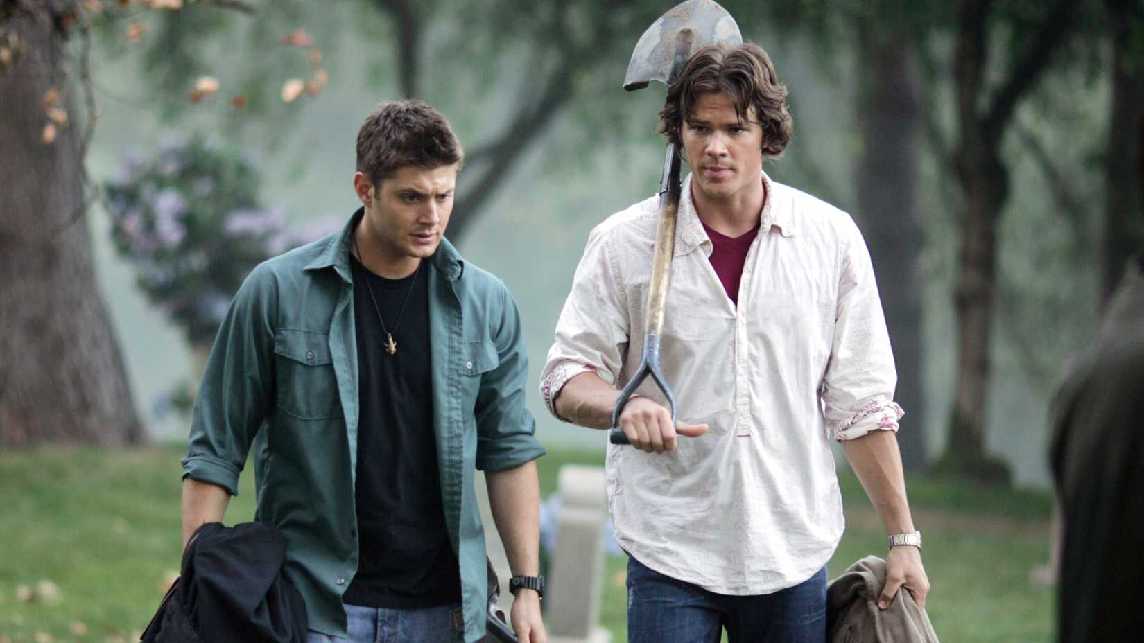 Jensen Ackles and Jared Padalecki walk with shovels as the Winchesters in Supernatural