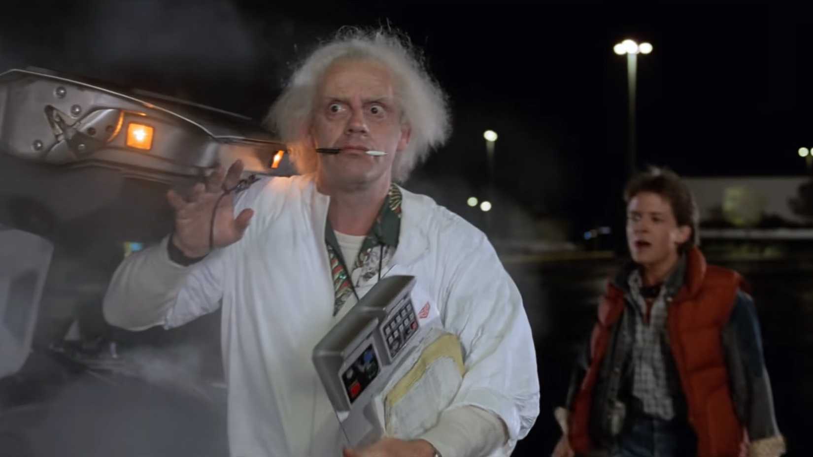 Christopher Lloyd con una penna in bocca nei panni di Doc Brown in un parcheggio in Ritorno al futuro