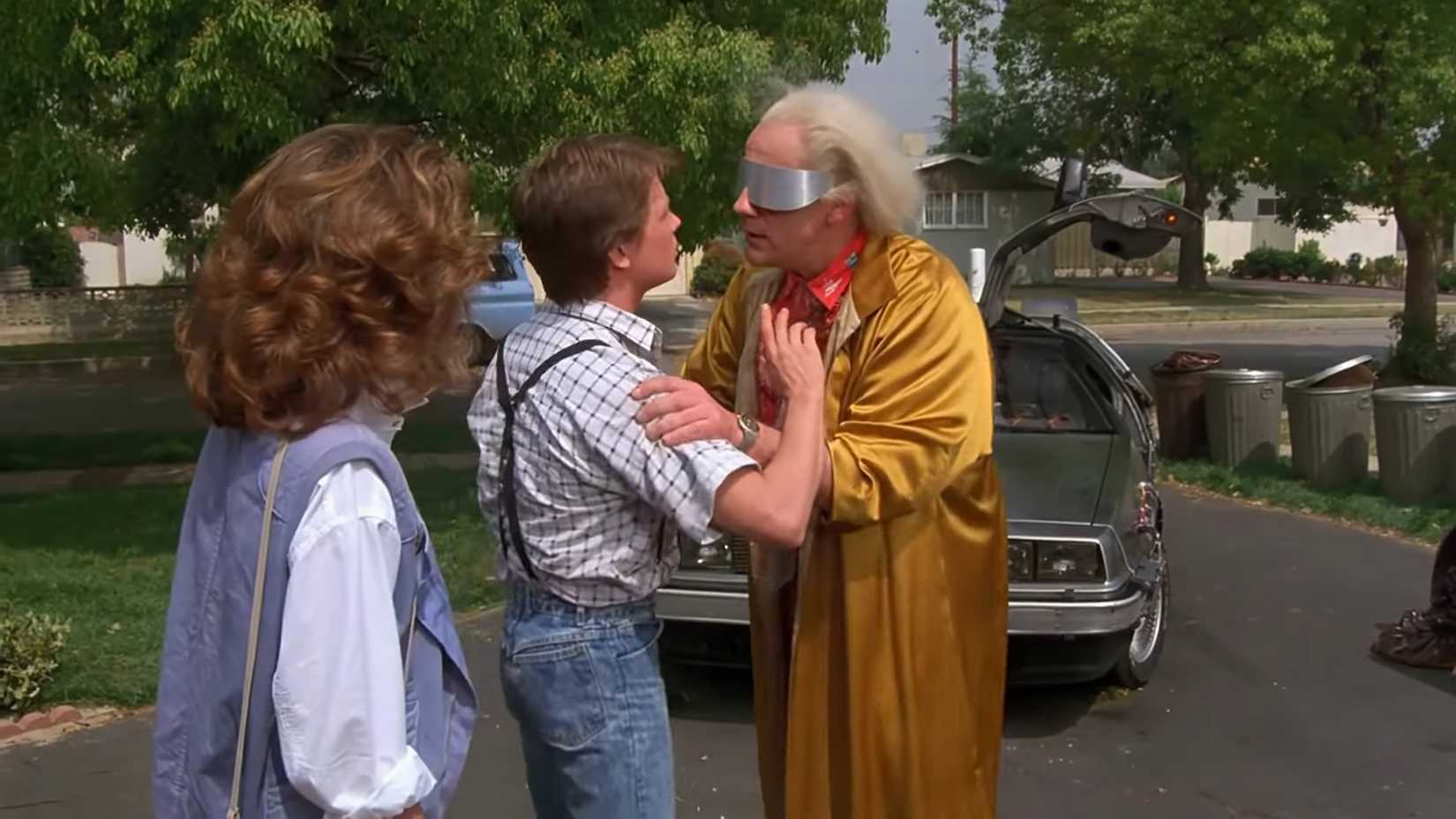 Christopher Lloyd nei panni di Doc Brown che tiene in braccio Marty su un vialetto in Ritorno al futuro