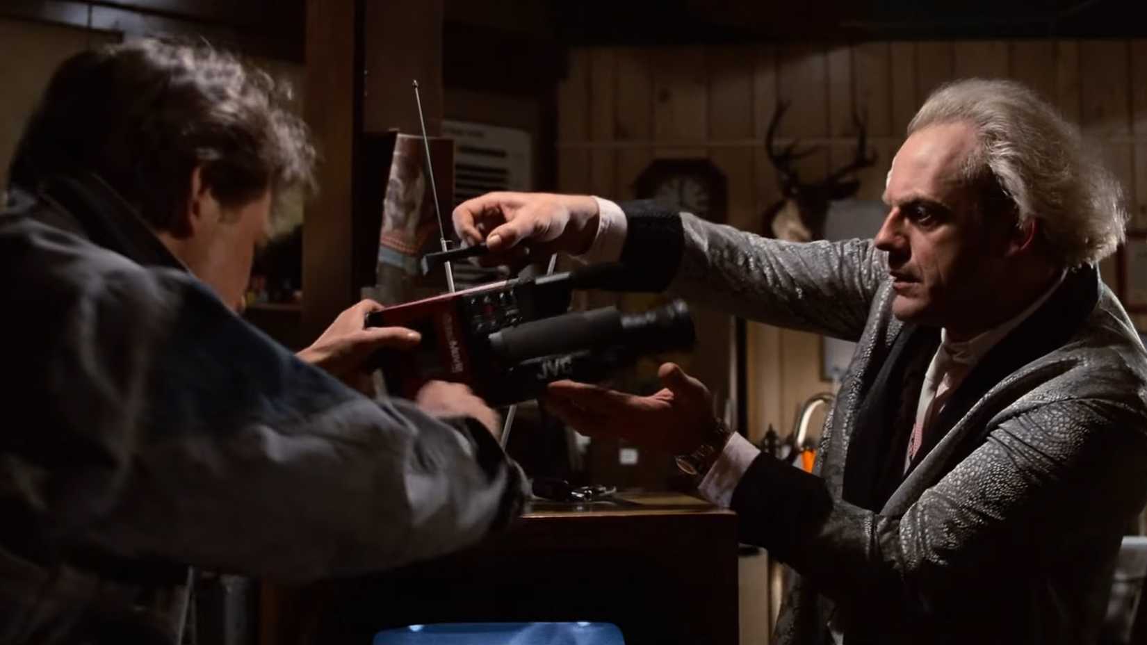 Christopher Lloyd nei panni di Doc Brown che tiene in mano una macchina fotografica insieme a Marty in Ritorno al futuro