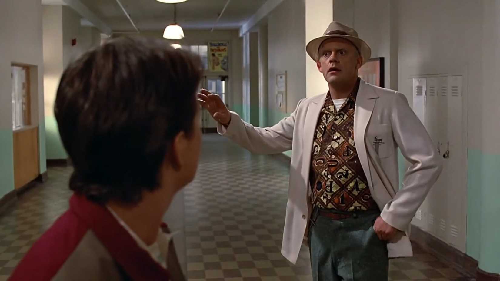 Christopher Lloyd nei panni di Doc Brown in piedi in un corridoio scolastico in Ritorno al futuro