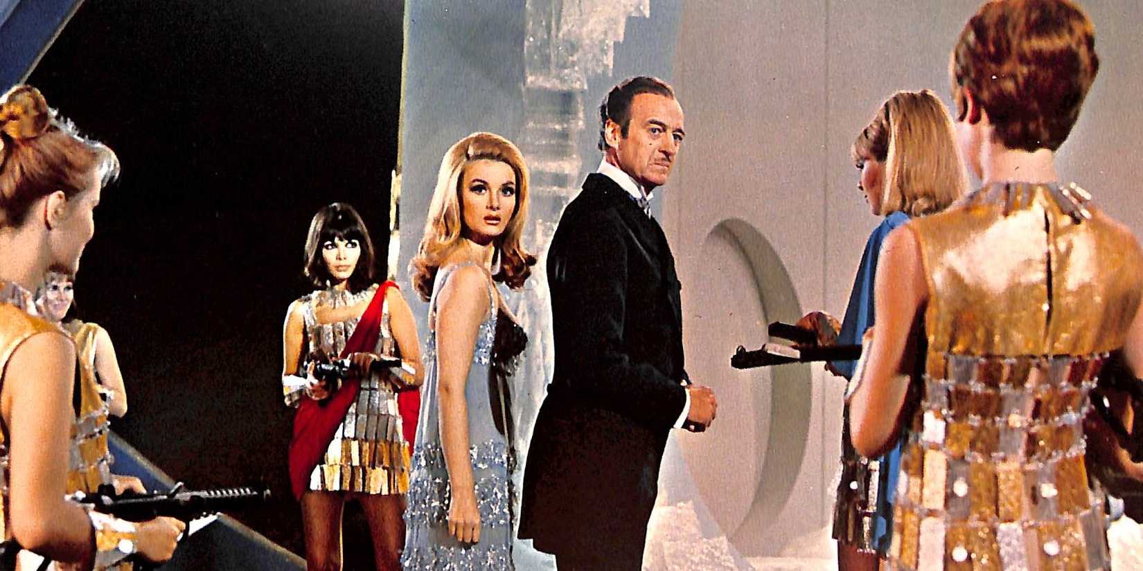 James bond nad Moneypenny surrounded by women with guns in Casino Royale