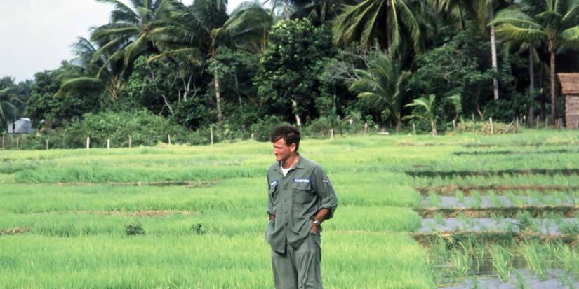 Robin Williams wearing a US army uniform and standing in a field in Good Morning, Vietname