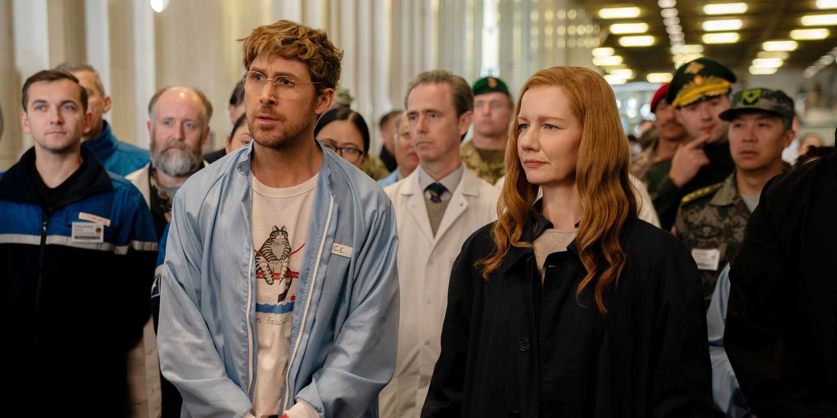 Ryan Gosling and Sandra Huller standing in a crowded room in Project Hail Mary.