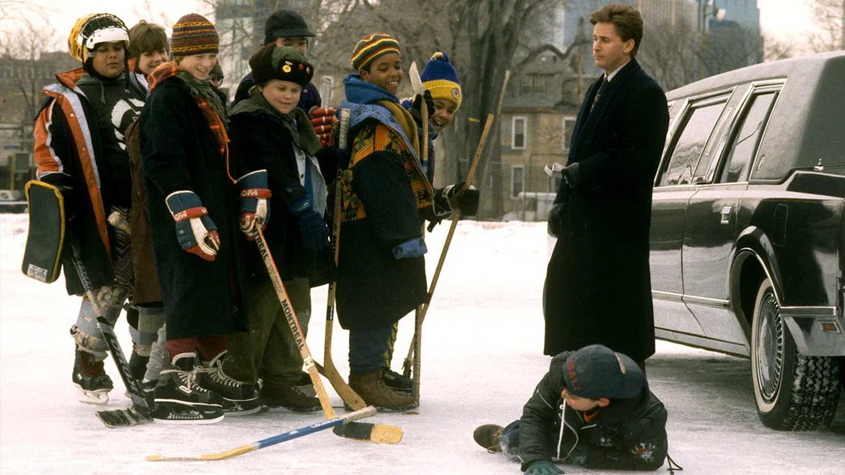 The mighty ducks team laugh at their fallen teammate while the coach looks on.