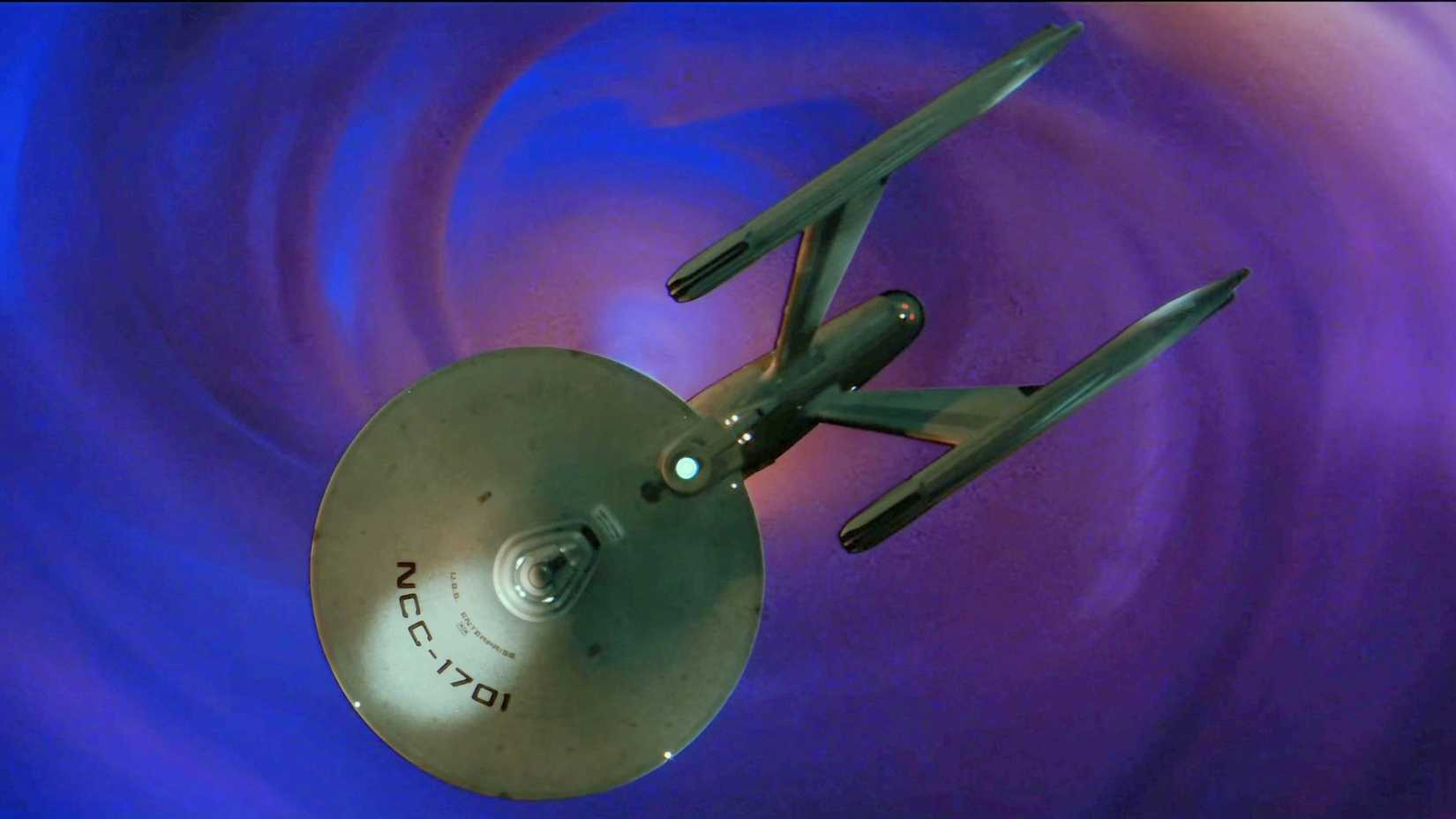 The USS Enterprise from the top down over a pink and purple swirling cloud of gas from Star Trek II The Wrath of Khan