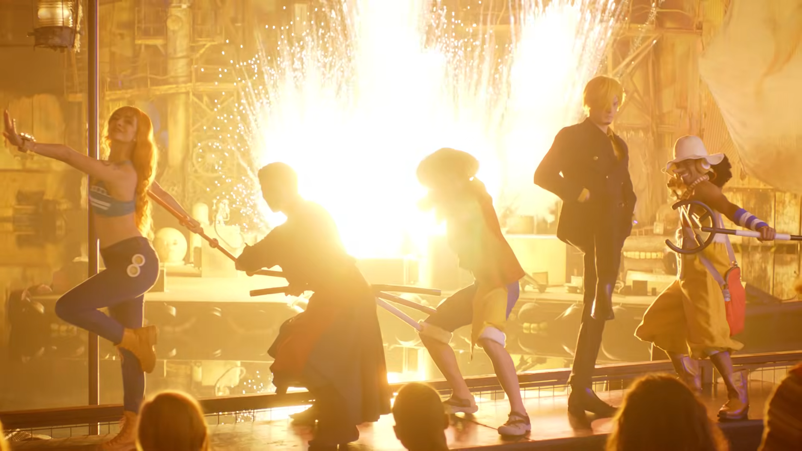 One Piece: Grand Pirate Show stunt actors for Nami, Zoro, Luffy, Sanji, and Usopp posing in front of a fireworks explosion