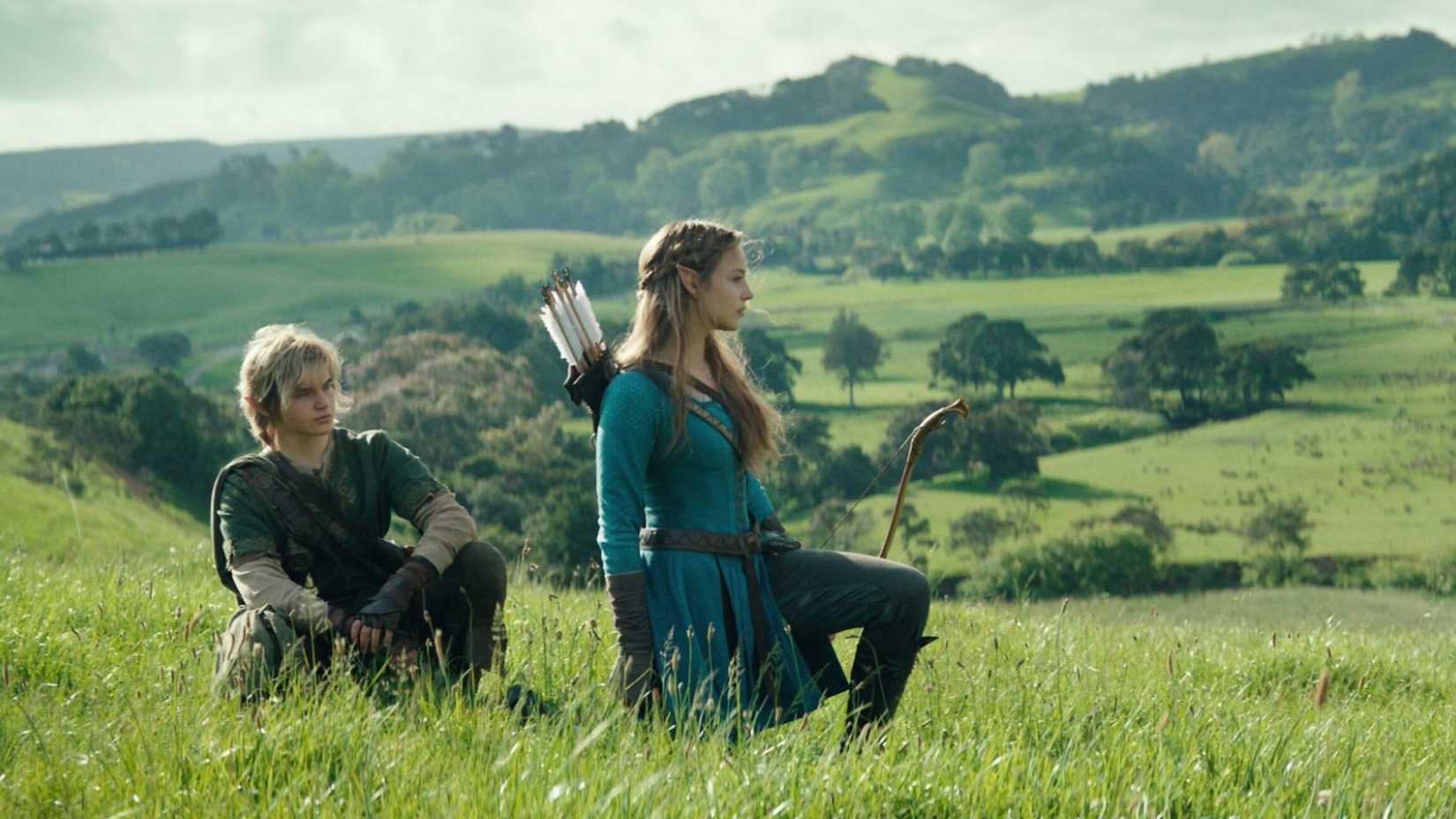 Link and Zelda sit in the grass with hills in the background.