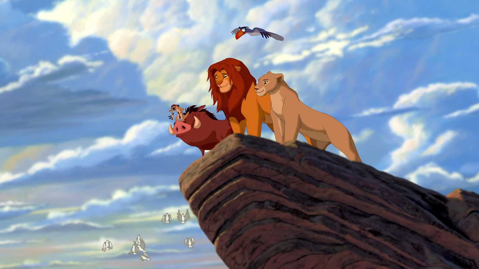 Simba, Pumbaa, Timon, Nala, and Zazu sit on Pride Rock in The Lion King.