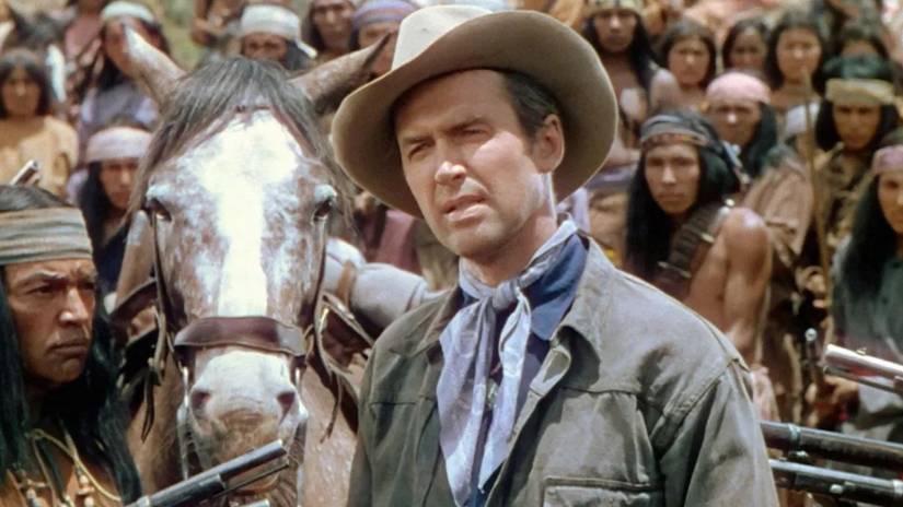 Jimmy Stewart standing in front of a horse and crowd in Broken Arrow