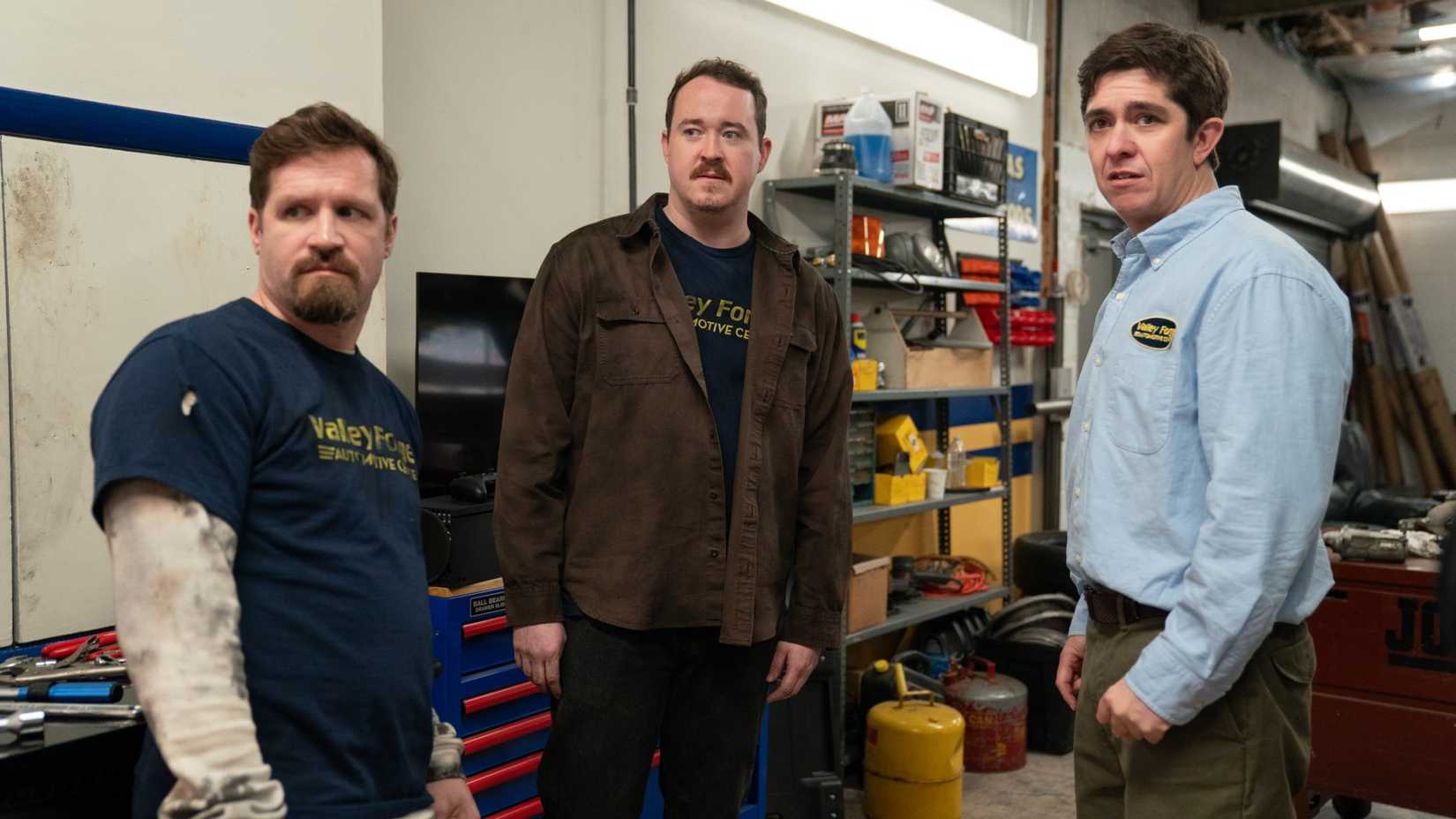 Chris O'Connor as Cal, Shane Gillis as Shane Jacobs, and Steve Gerben as Will Jacobs standing next to each other at the auto-repair shop on Tires.