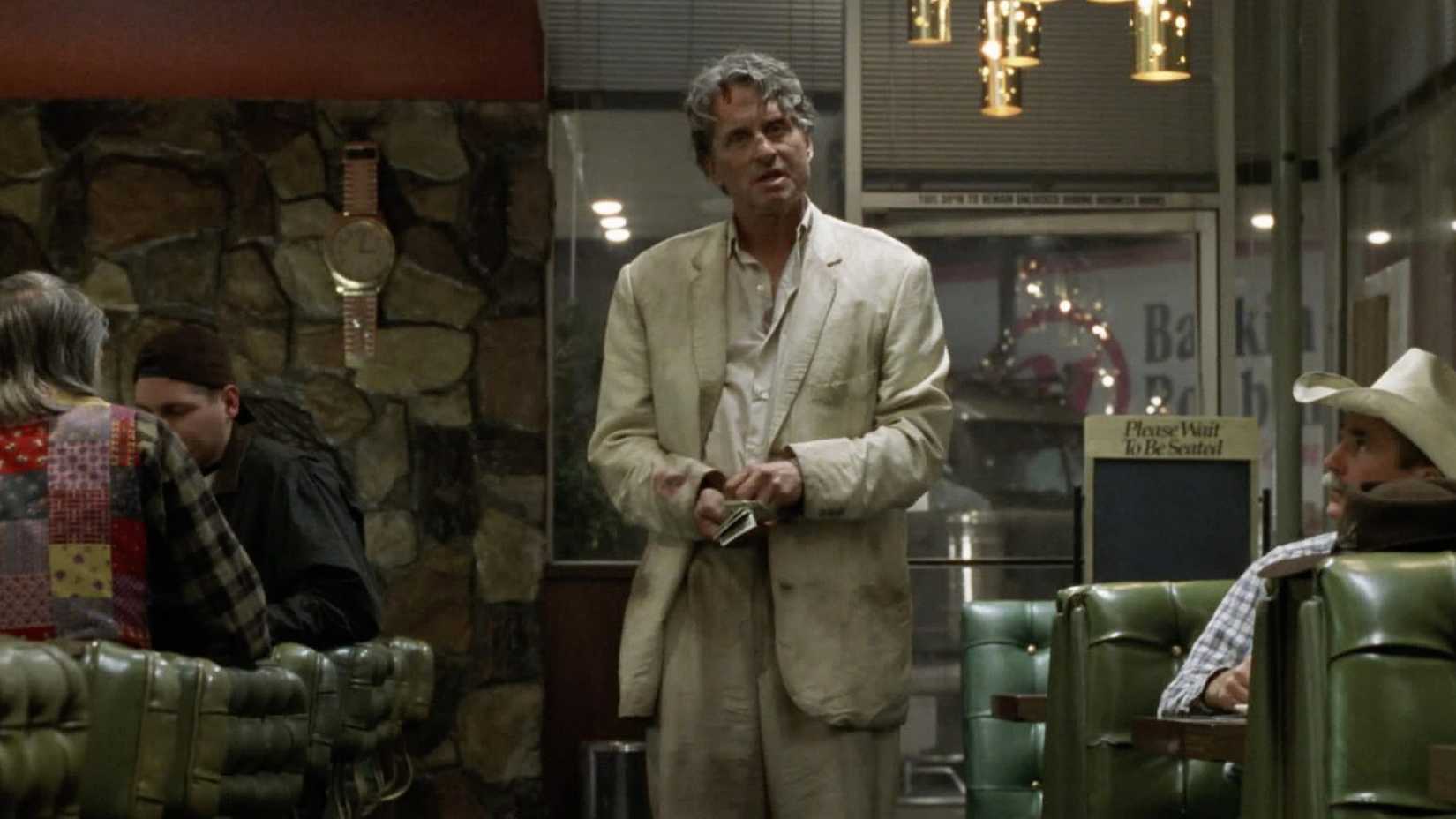Michael Douglas stands in the middle of a restaurant looking disheveled in The Game.