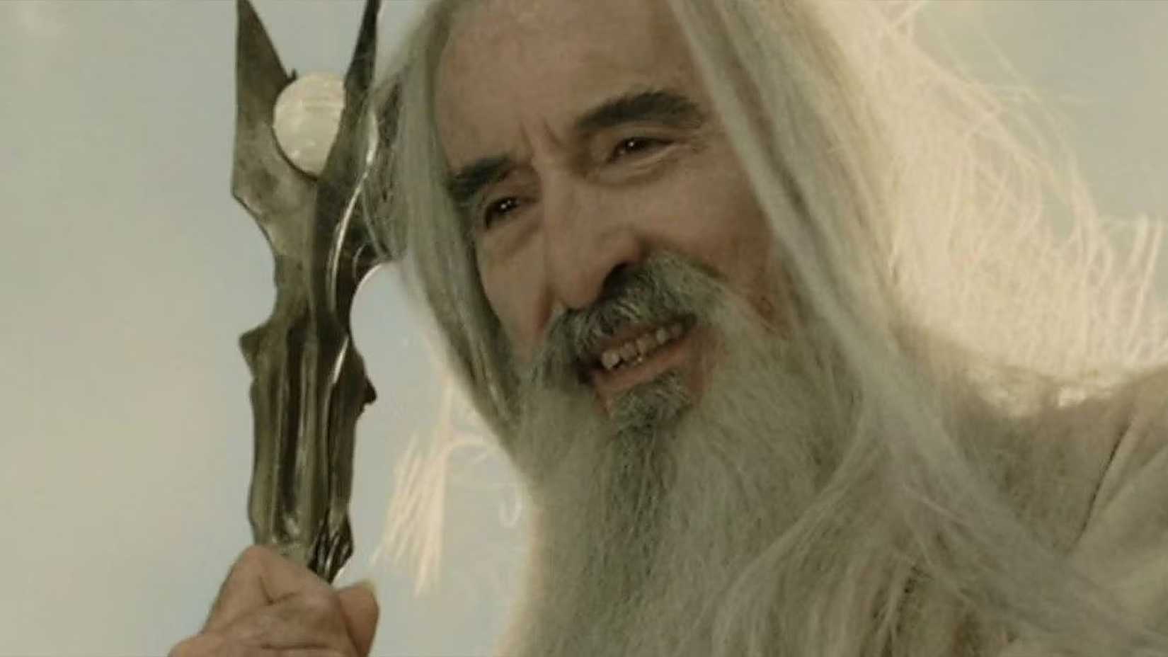 Saruman grins as he holds his staff in The Lord of the Rings. 